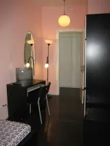 Escritorio con silla, espejo ovalado y lámpara de pie junto a la puerta de la habitación